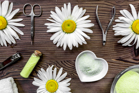 preparation for manicure with chamomile on dark wooden background top view.の写真素材