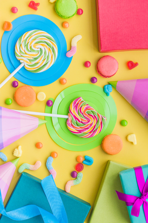 Birthday concept with wrapped gifts, greeting cards and sweets on yellow background top viewの写真素材