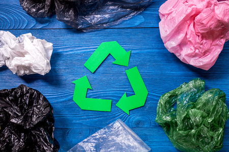 Paper recycle sign with plastic garbage on blue wooden background top viewの写真素材