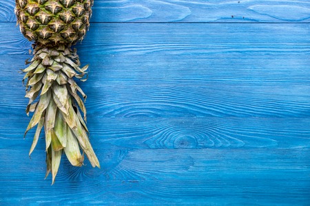 Pineapple and leaves on blue wooden desk background top view copyspaceの写真素材