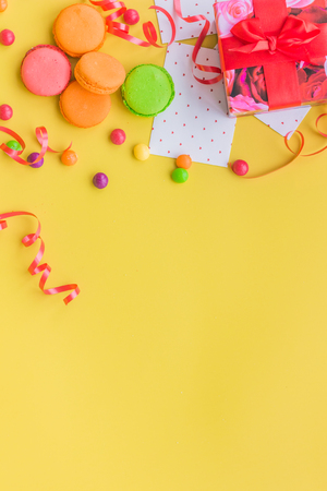 Birthday concept with wrapped gift and sweets on yellow background top view copyspaceの写真素材