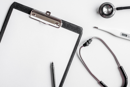 Modern medicine workplace with board, stethoscope white table flat lay space for textの写真素材