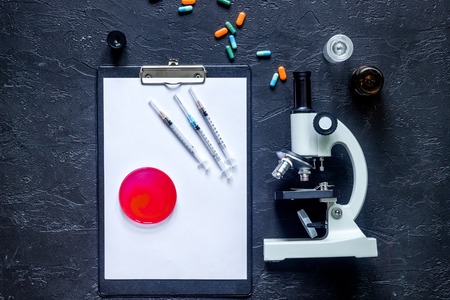 Workplace of doctor. Pad, keyboard, microscope, syringe, Petri dish on grey stone background top view.の写真素材