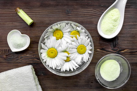 Spa composition on dark wooden desk with chamomile, towel and salt top view.の写真素材