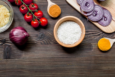 paella ingredients with rice, salt, spices and tomatoes on wooden table background top view mockupの写真素材