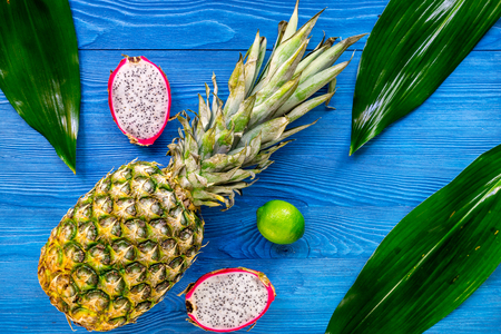 Pineapple, dragonfruit and lime on blue wooden desk background top viewの写真素材