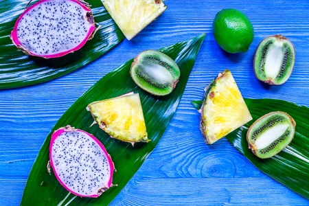 Pieces of exotic fruits. Dragonfruit, pineapple and kiwi on blue wooden background top view copyspaceの写真素材
