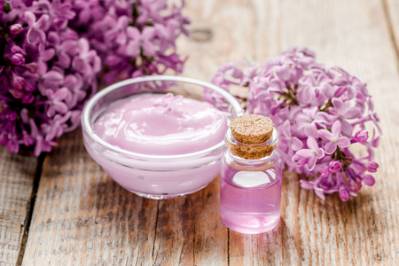 Spa cosmetic set with lilac flowers wooden desk backgroundの写真素材