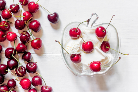 Ice cream decorated with fresh cherry on white table background top view.の写真素材