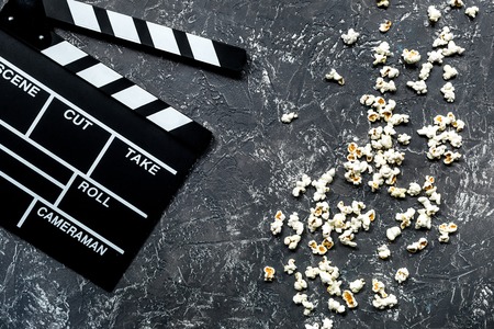 Watching the film. Movie clapperboard and popcorn on grey stone table background top view.の写真素材