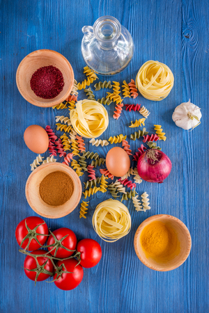 Food ingredients for Italian spaghetti on blue wooden desk background top view.の写真素材