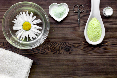 Spa composition on dark wooden desk with chamomile, towel and sciccprs top view copyspace.の写真素材