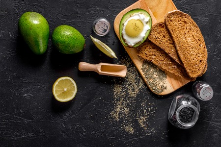 Light breakfast with avocado, rye bread and fried eggs on black stone table top view.の写真素材