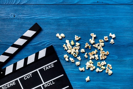 Watching the film. Movie clapperboard and popcorn on wooden table background top view.の写真素材