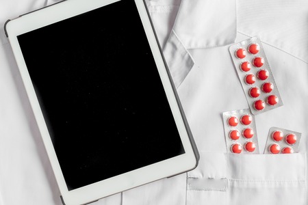 Doctor's work desk in hospital with stethoscope and tablet on overall background top view mockupの写真素材
