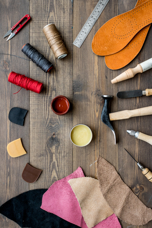 Set of cobbler tools on brown wooden desk background top view.の写真素材