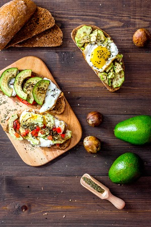 Vegetarian breakfast. Sandwiches with avocado, fried eggs and paprika on wooden table top viewの写真素材