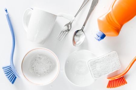 Dishwashing liquid and sponge on white background top view.
