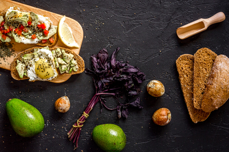 Light breakfast. Sandwiches with avocado and fried eggs on black stone table top view.の写真素材