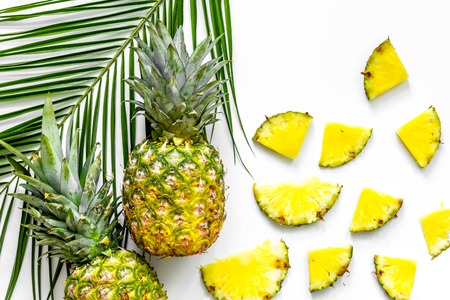 Pineapples and palm branch on white background top view.の写真素材