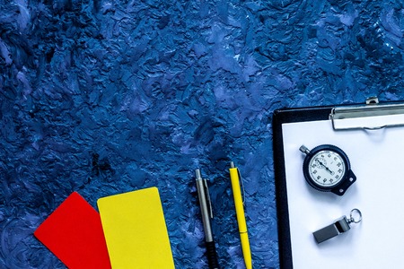 Set to judge competition. Yellow and red cards, stopwatch, whistle, pad, pen on blue table background top view.の写真素材