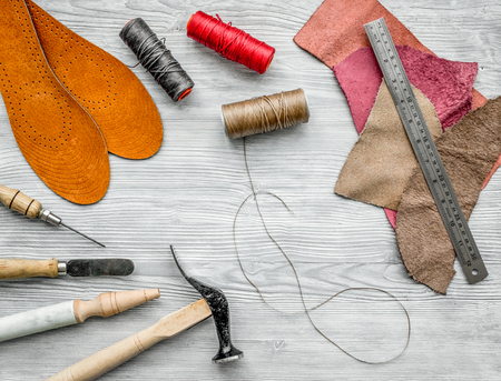 Working place of shoemaker. Skin and tools on grey wooden desk background top view.の写真素材