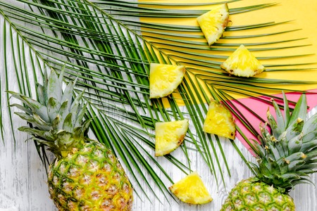 Pineapple and palm branch on wooden desk background top view.の写真素材