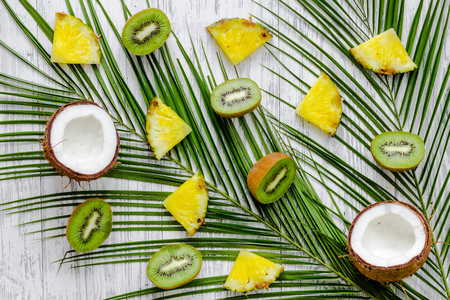 Summer exotic fruits. Kiwi, cocount and palm branch on white background top view.の写真素材