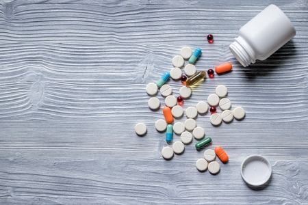 Vitamins and supplements. Pills and pill bottle on grey table background top view.
