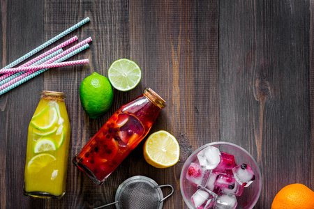 Bottle of fresh lemonade, fruits and ice cubes on wooden background top view.の写真素材