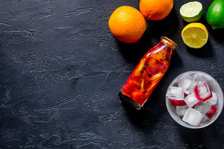 Bottle of fresh lemonade, fruits and ice cubes on black stone background top view.の写真素材