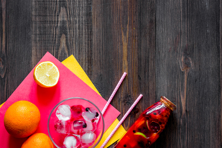 Bottle with fresh lemonade, fruits and ice cubes on wooden background top view.の写真素材