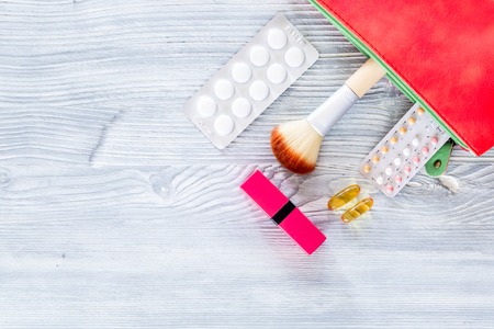 Contents of wonam's beauty bag. Cosmetics, contraceptives and pills on wooden table background top view.の写真素材