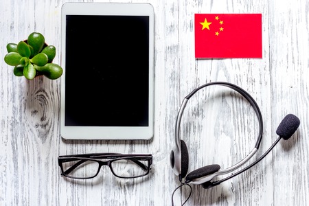 Self-development. Learning languages online. Headphones and tablet PC on wooden background top view.の写真素材