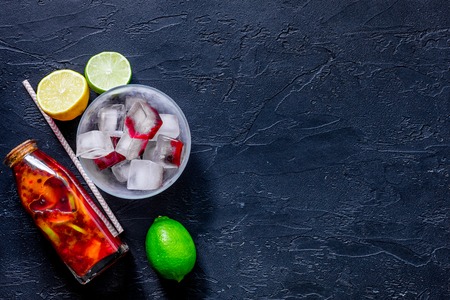Bottle of fresh lemonade, fruits and ice cubes on black stone background top view.の写真素材