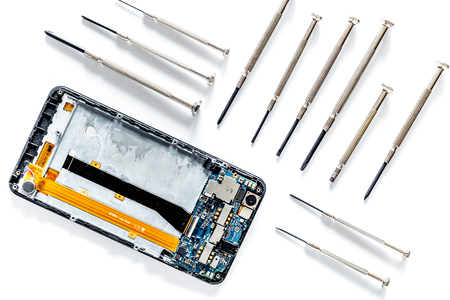 Parts of disassembled cell phone and screwdrivers on white background top viewの写真素材