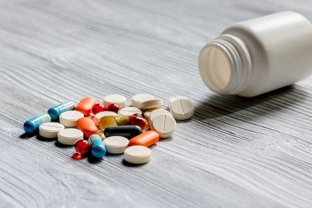 Pills and pill bottle on grey table backgroundの写真素材