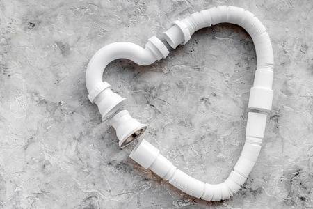 Disassembled sink drain pipe heart shaped on grey stone background top view copyspaceの写真素材