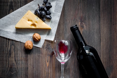 Wine snack. Cheese, nuts, grape on dark wooden table background top view copyspaceの写真素材