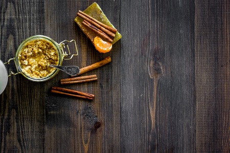 Homemade organic scrub in glass jar and soap with orange and cinnamon on dark wooden background top view copyspaceの写真素材