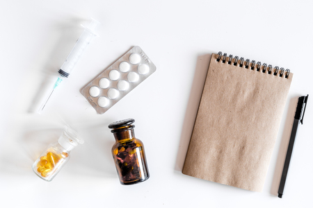 Doctor's work table in clinic. Pills, syringe and notebook on white background top view.の写真素材