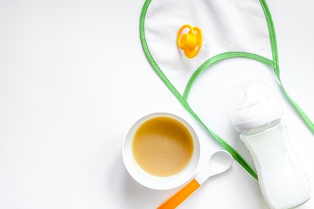Preparing to feed baby. Puree, spoon and bib on white background top view.の写真素材