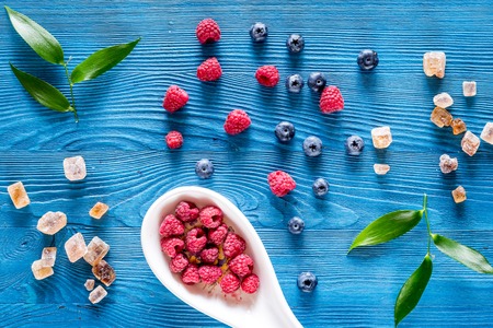Preparing raspberry jam. Berries and sugar on blue wooden background top view.の写真素材