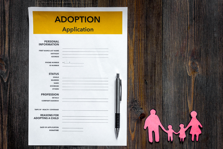 Adoption application on wooden table background top view.