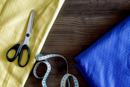 Clothing designer workplace. Measuring tape and sciccors on dark wooden table background top view.の写真素材