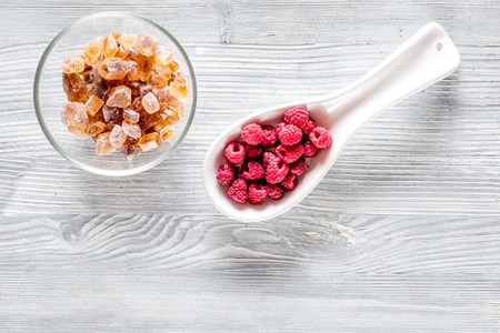 Making raspberry jam. Berries and sugar on grey wooden background top view copyspace