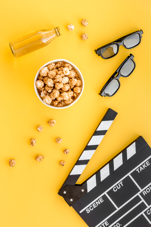 Snacks for film watching. Popcorn and soda near clapperboard, glasses on yellow background top viewの写真素材