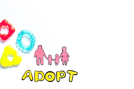Adopt word, paper silhouette of family and toys on white background top view copyspaceの写真素材