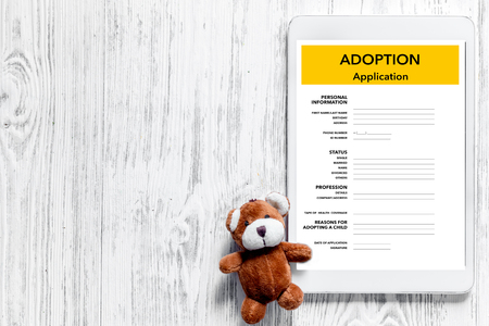 Adoption application near toy on light wooden table background top view copyspaceの写真素材