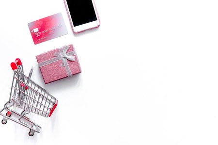 Mobile shopping. Shopping cart, phone, gift box on white background top view.の写真素材